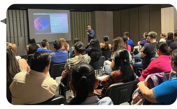 Carlos Sánchez Ortiz dando una conferencia a un grupo de personas, presentando información sobre las adicciones y el cerebro.