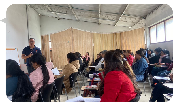 Carlos Sánchez Ortiz dando una conferencia a un grupo de personas en un aula, enfocándose en temas de adicciones y salud emocional.