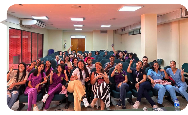 María del Pilar Pinzón Rueda posando con un gran grupo de estudiantes y profesionales de la salud en un auditorio.