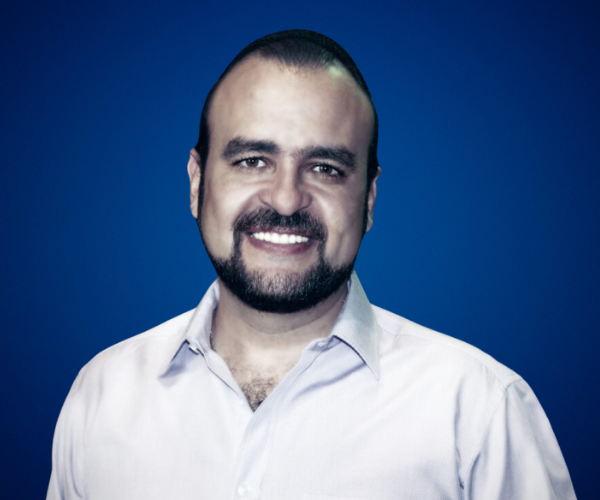 Fotografía de Alfonso Navarro, sonriendo frente a un fondo azul liso, vestido con camisa clara y con expresión amigable y profesional.