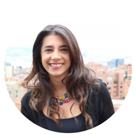 Fotografía de Pilar Ibañez, sonriente en una terraza con vista urbana al fondo, luciendo chaqueta negra y collar colorido, con luz natural.
